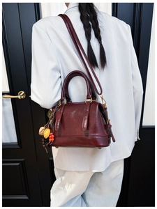 Detail of burgundy glossy leather handbag featuring ethnic charm and adjustable strap