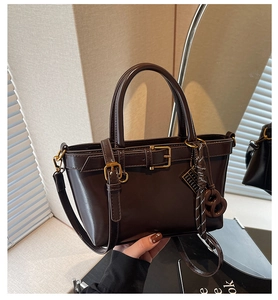 Detail of vintage dark brown faux leather tote with gold buckle and woven charm