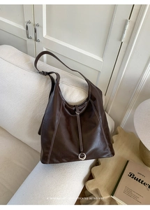 Detail of vintage brown tote bag with white contrast stitching and round metal buckle