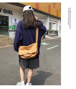 Detail showing khaki canvas crossbody bag with large flap design on shoulder