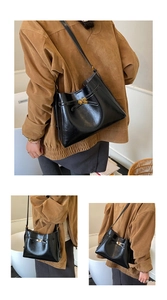 Détail d'un sac à bandoulière en cuir noir brillant avec fermoir tournant en métal doré