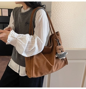 Brown soft leather tote bag with bear charm detail shown on model with casual outfit