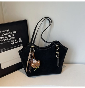 Black suede tote bag detail with white stitching, gold buckle, and bear charms