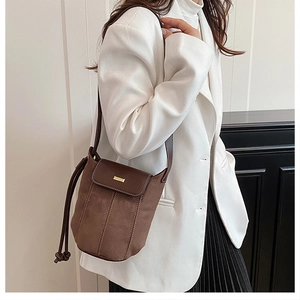 Detail view of the brown suede and leather patchwork crossbody bag on white blazer