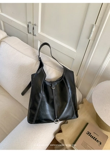 Detailed close-up of large black tote bag with white contrast stitching and silver buckle