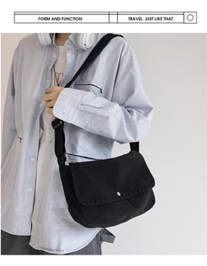 Detail of minimalist black canvas messenger bag with flap closure and adjustable strap