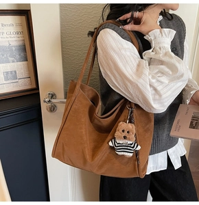 Brown faux leather tote bag detail with cute teddy bear charm and sleek shoulder strap