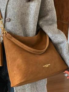 Vintage brown suede hobo bag with topstitching and gold hardware in a home setting