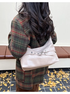 Hobo style cream PU leather shoulder bag with decorative straps and metallic eyelets