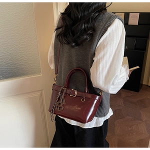 Detail showing a burgundy vintage mini square handbag with gold buckle on a model