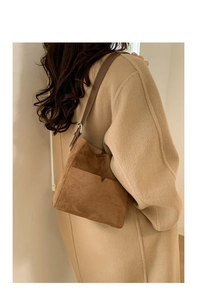 Détail d'un grand sac seau en daim marron avec poches superposées en V et bandoulière en cuir