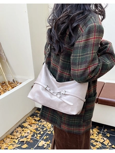 Beige oversized hobo bag worn by model in a checkered blazer on an autumn street