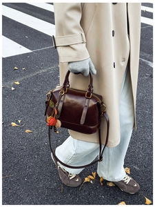 Detail of dark brown vintage Boston bag with gold hardware carried on a city street