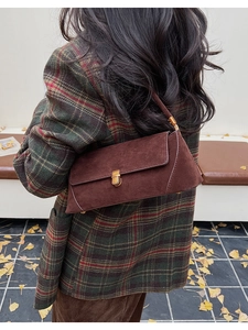 Dettaglio di una borsa baguette in pelle scamosciata marrone caffè con fibbia dorata