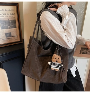 Detail view of deep brown vintage tote bag with a cute bear charm on an aesthetic background