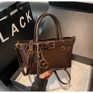 Close-up of a vintage dark brown handbag with glossy finish and decorative buckles
