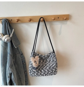 Gros plan du sac bandoulière en tweed noir et blanc avec un ours en peluche sur crochet