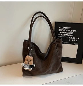 Detail of deep brown retro tote bag featuring a cute plush bear charm on white background