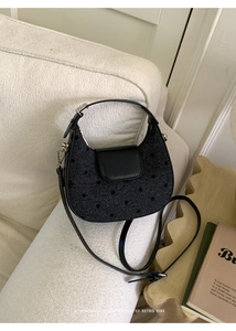 Détail d'un sac demi-lune noir à pois avec un nœud rétro sur un canapé crème