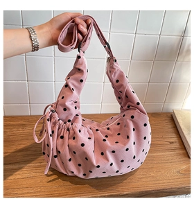 Detail of pink corduroy tote bag featuring black polka dots and adjustable shoulder strap