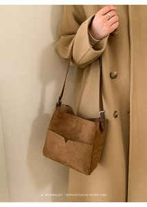 Gros plan détaillé du sac seau en daim marron avec poche en V sur un manteau en laine camel