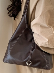 Large brown tote bag with white stitching and silver ring detail shown on shoulder