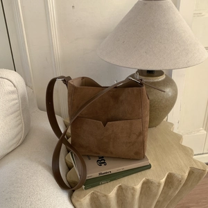 Detail of vintage brown bucket bag with unique V-shaped front pocket and matte suede texture