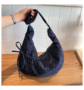 Detail of blue corduroy tote bag with black polka dots and side drawstring bow design