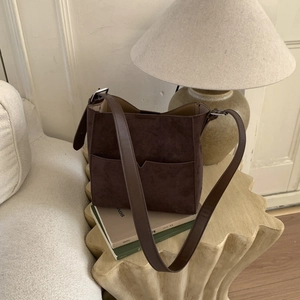 Detailed macro view of dark brown frosted suede shoulder bag with retro bucket design