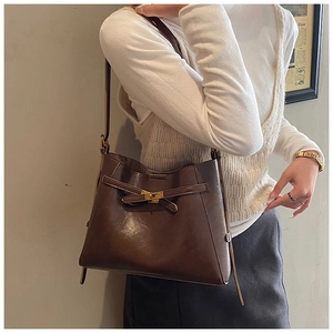 Détail du sac bandoulière en cuir marron foncé avec fermoir tournant doré élégant