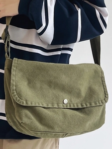 Minimalist military green canvas messenger bag with adjustable strap worn by model