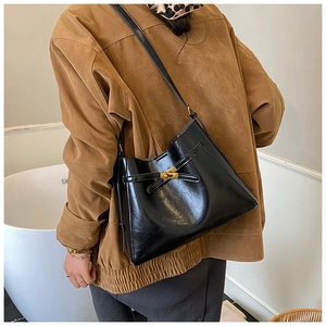 Gros plan sur un sac à main noir brillant doté d'un fermoir tournant en métal doré classique