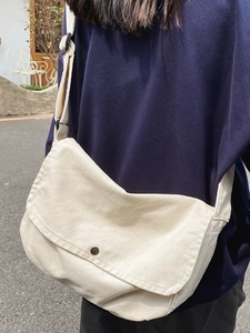 Minimalist beige canvas messenger bag for women with round metal buckle and large flap design