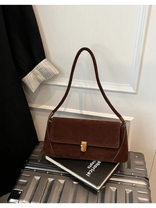 Dettaglio della borsa baguette in pelle scamosciata marrone con chiusura dorata
