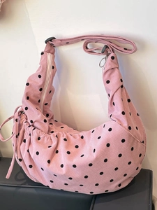 Pink corduroy crescent tote bag with black polka dots and adjustable shoulder strap