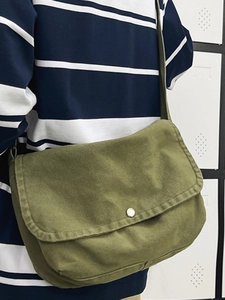 Minimalist dark green canvas messenger bag with flap closure shown on model