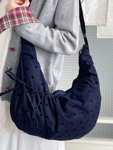 Navy blue polka dot crescent tote bag with drawstring detail and metal zipper