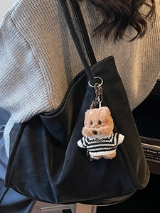 Large black suede tote bag with plush bear charm shown in a cozy indoor scene