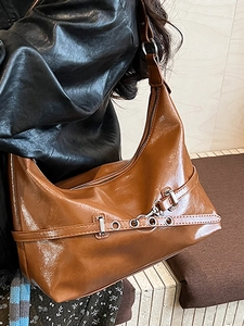 Brown vintage faux leather underarm bag with glossy finish and metal eyelet belt decoration