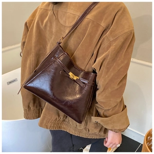 Détail d'un sac à bandoulière en cuir marron foncé brillant avec boucle métallique