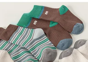 Close-up of knit cotton socks featuring elastic ribbed cuffs and embroidered letter m detail