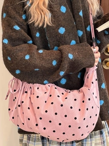 Pink polka dot corduroy hobo bag with drawstring closure for women on a model