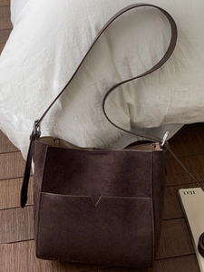 Vintage dark brown faux suede bucket bag with adjustable strap on wooden floor