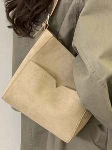 Minimalist beige suede bucket bag with front V-shaped pocket and thin shoulder strap