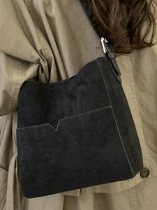 Minimalist black suede shoulder tote bag featuring a V-shaped front pocket and silver buckle