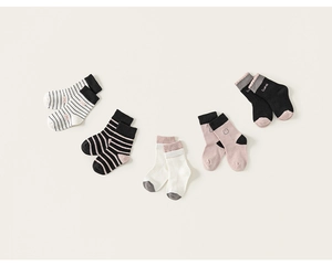 Close-up of five pairs of children's cotton socks with retro stripes and solid patterns