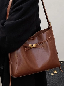 Sac fourre-tout chic en cuir marron avec fermoir doré dans un décor de rue minimaliste