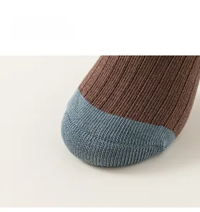 Close-up of children's cotton socks showing brown and blue patchwork toe and ribbed texture
