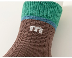 Detail view of children's cotton knit socks with green and blue stripes and M logo