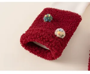 Detailed close-up of child's red fleece leg cuffs featuring colorful plush ball accents